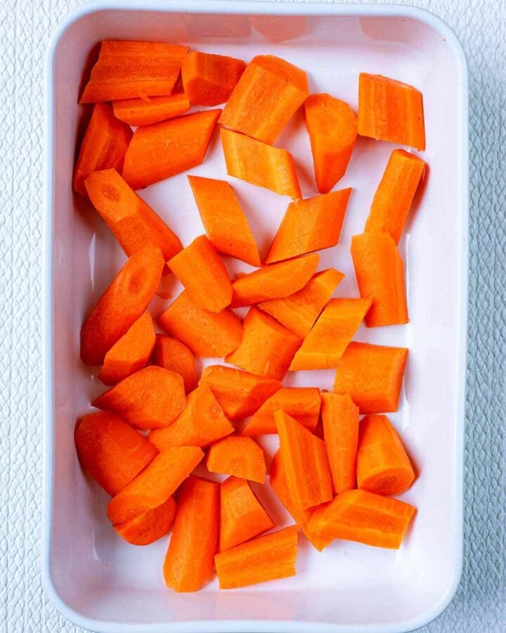 A white baking dish containing chopped raw carrots.