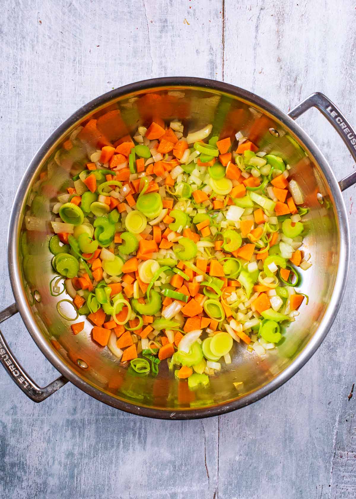 Onions, carrots, celery, garlic and leek in a large silver pan.