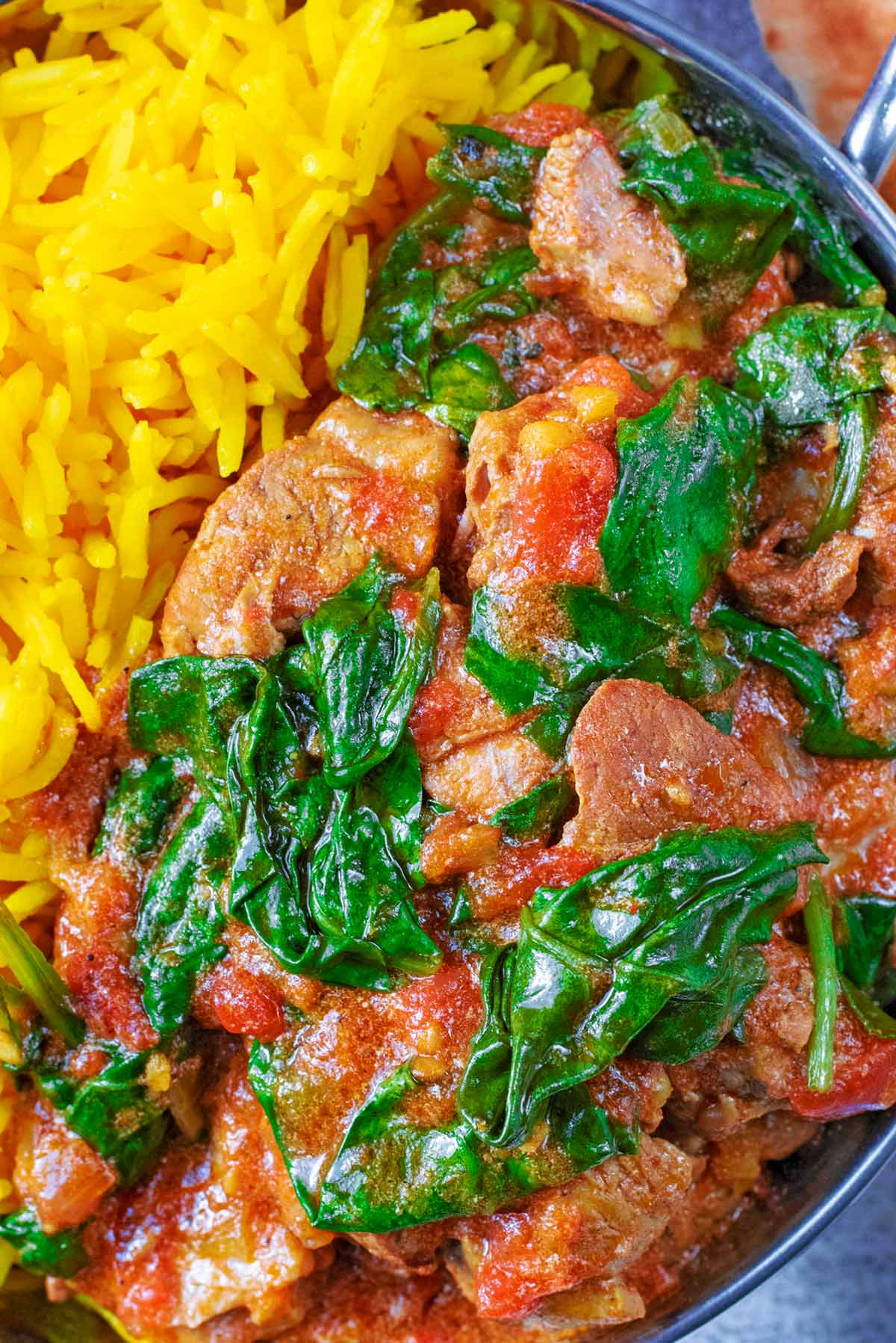 Lamb and spinach in a curry with bright yellow rice.