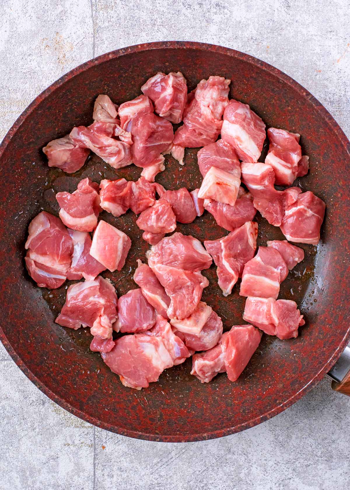 Chunks of lamb cooking in a frying pan.