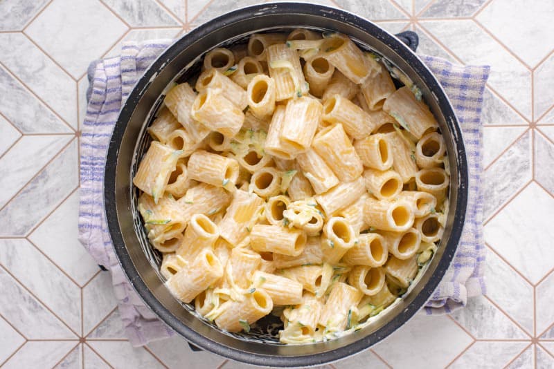 A saucepan containing cooked rigatoni pasta in a creamy sauce.