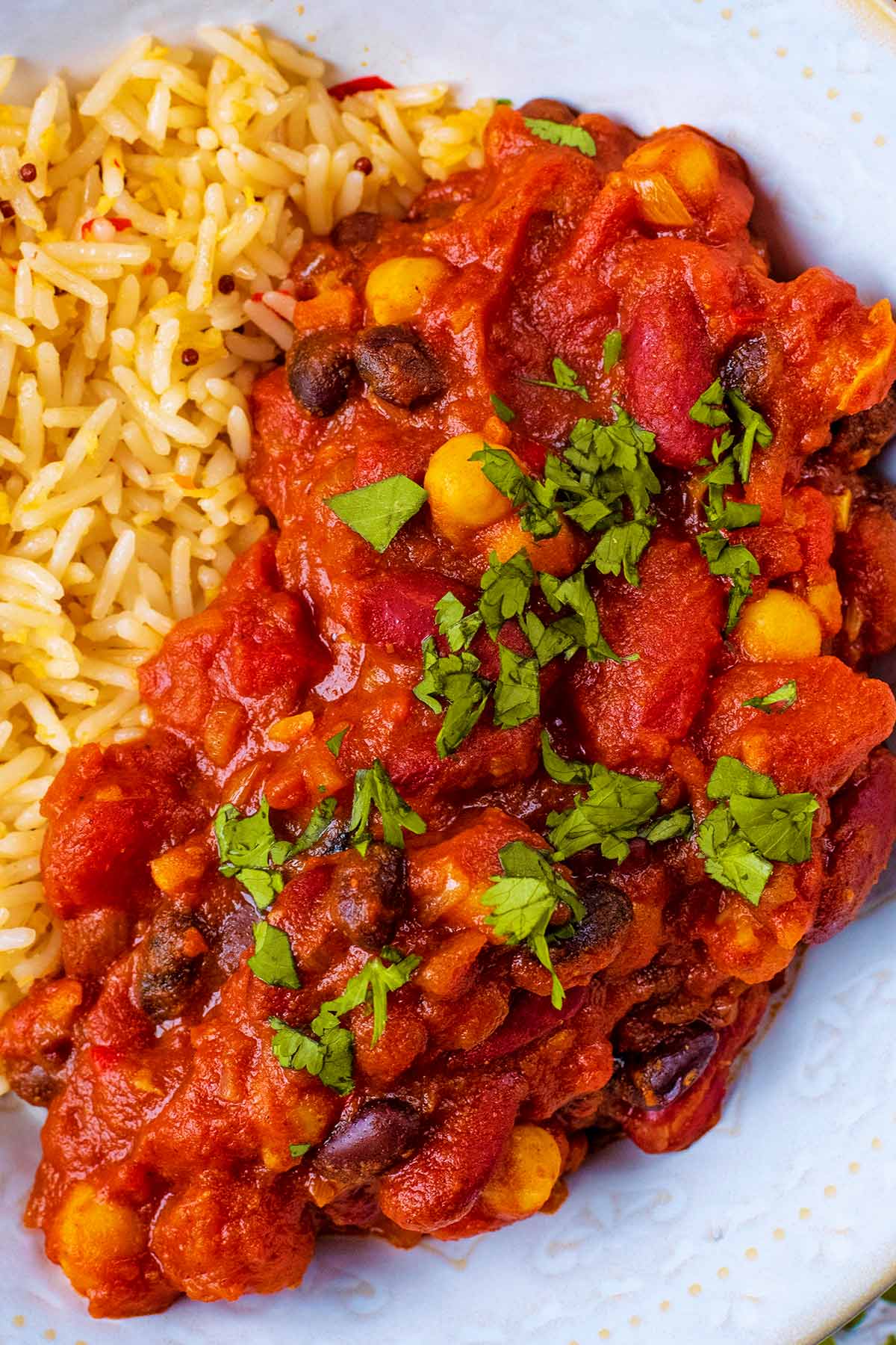 A bowl of bean Curry with rice. Chopped coriander on top.