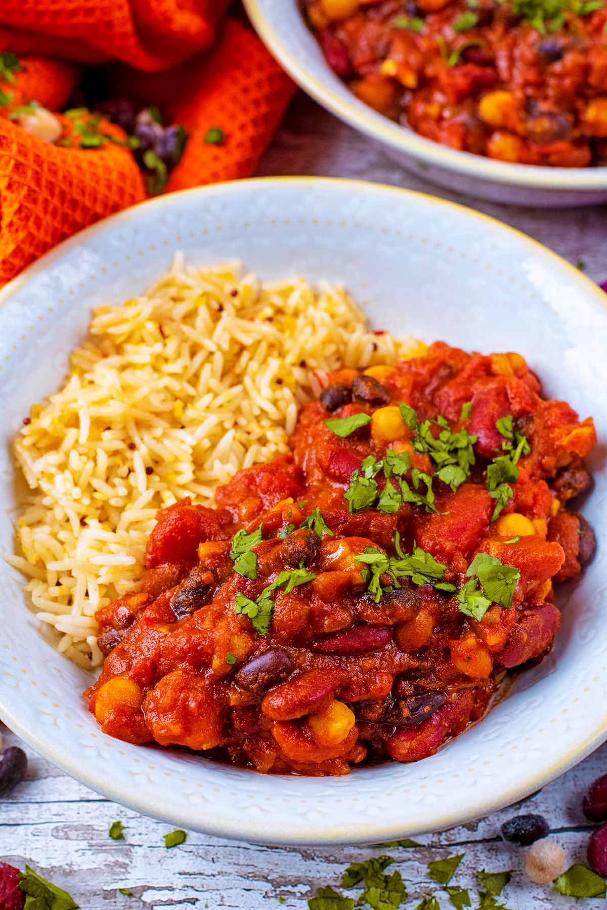 A bowl of bean curry and rice with another bowl in the background.