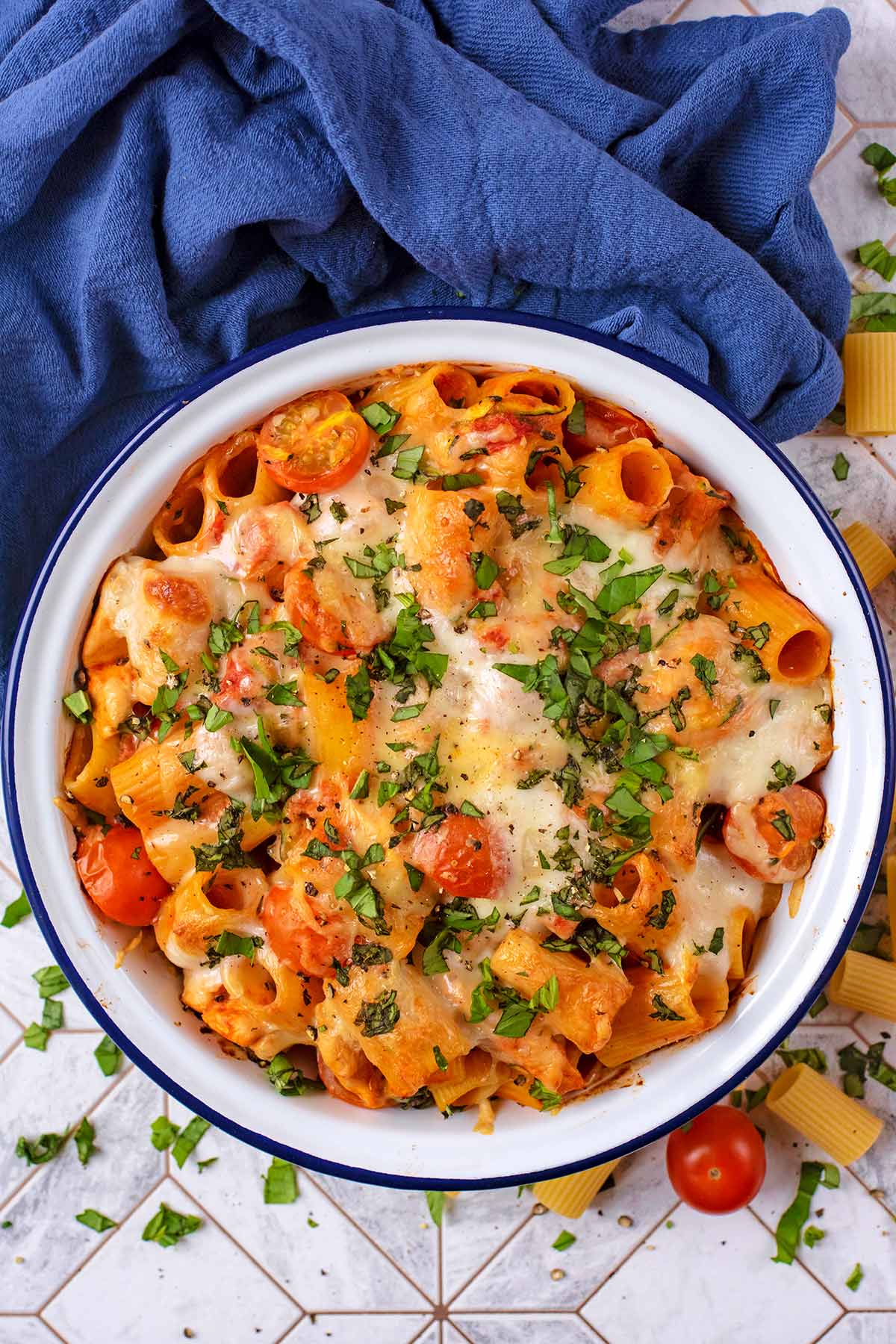 Pasta bake in a white bowl, next to a blue towel.