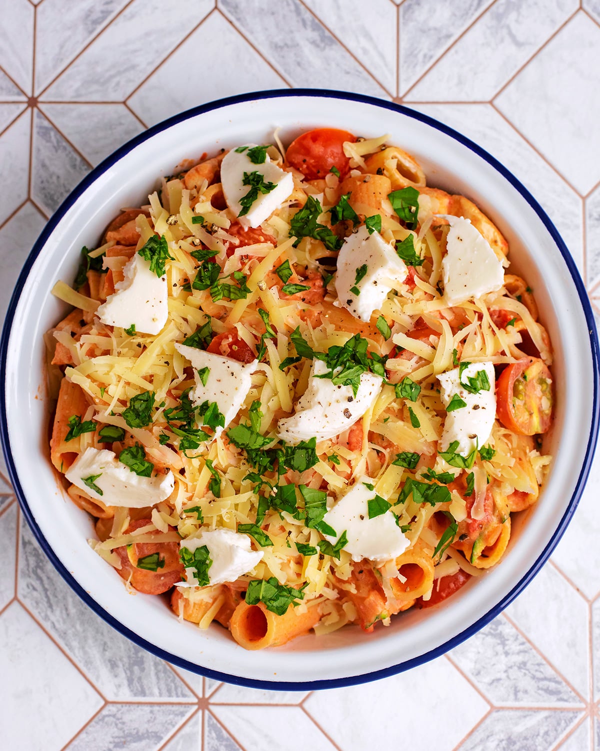 The pasta and sauce in a baking dish with cheese on top.