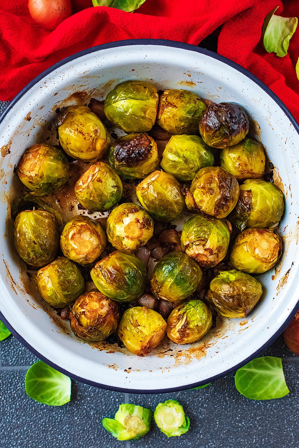 A white dish with Roasted Brussels Sprouts. A red towel is next to it.