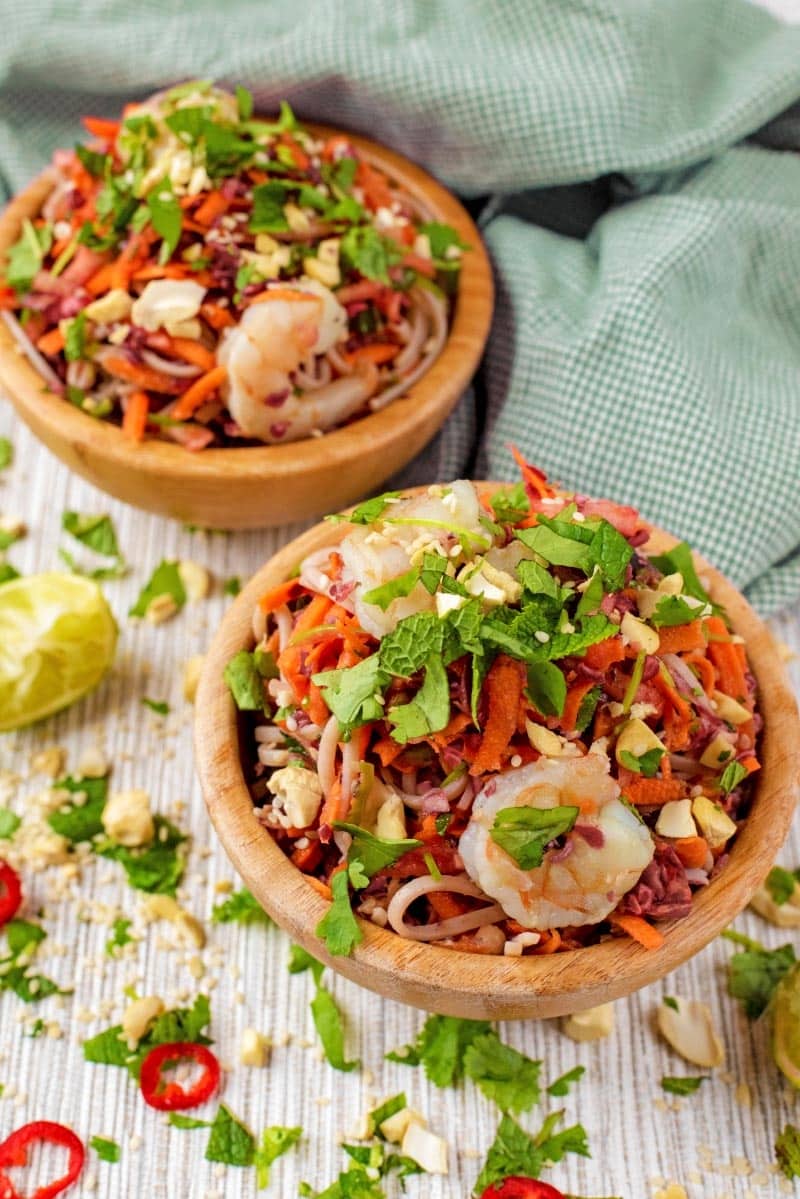Garlic Prawn Noodles in wooden bowls with scattered coriander and sliced chillis.