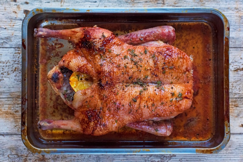 A whole cooked duck in a roasting pan.