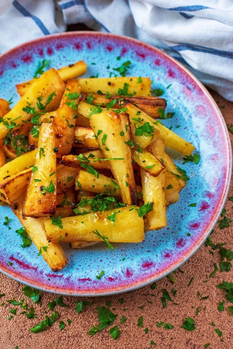A plate of cooked parsnips sprinkled with herbs.