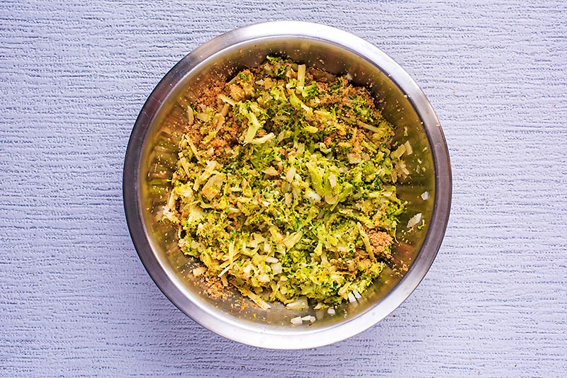 Broccoli, onion, breadcrumbs and cheese all mixed together in a bowl.