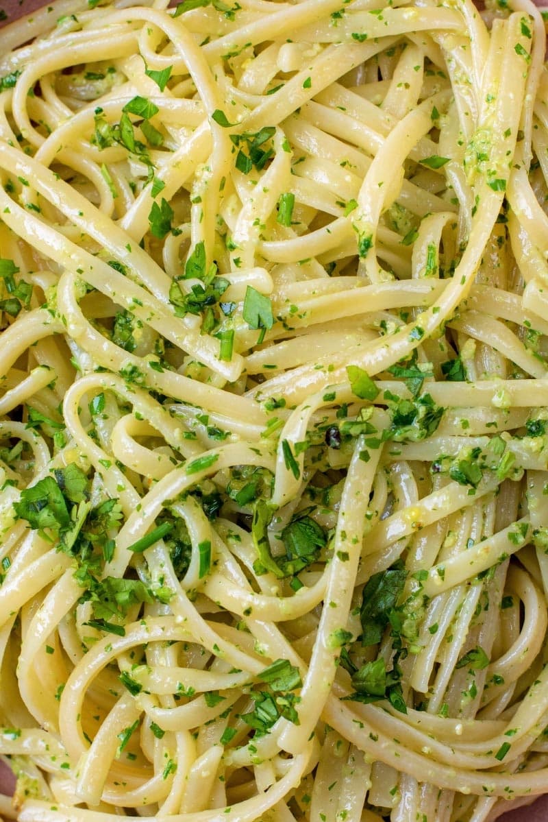 Spaghetti mixed with pesto and sprinkles with chopped herbs.