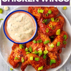Oven baked chicken wings and sauce on a plate with a text title overlay.