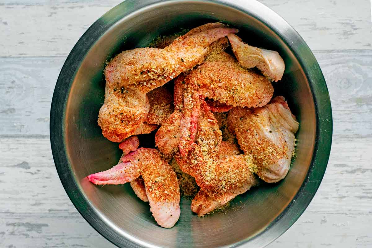 A bowl containing chicken wings coated in seasoning.