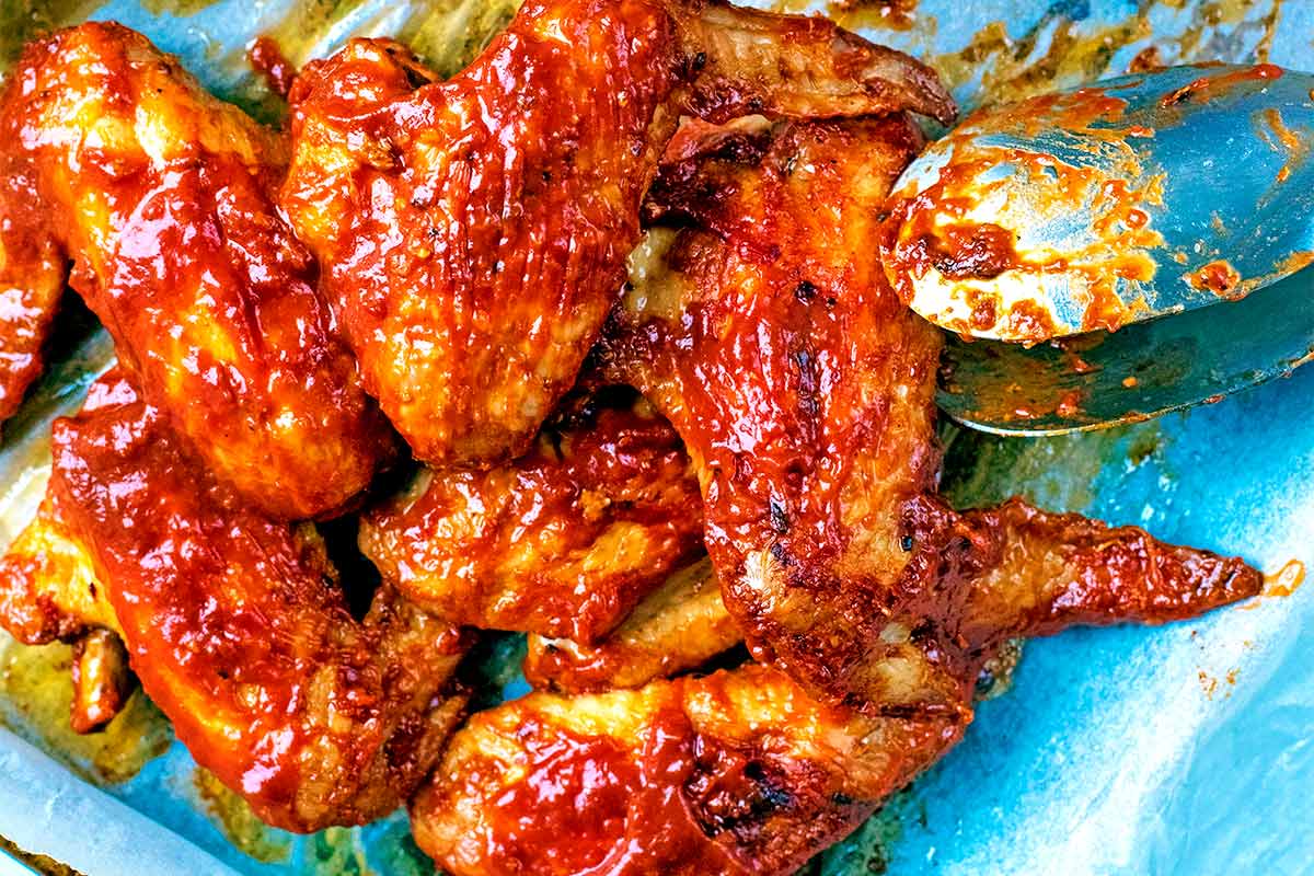 Cooked chicken wings coated in barbecue sauce.
