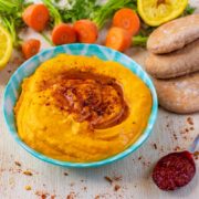 Roasted Carrot Hummus in a blue dish next to some pitta bread and carrots