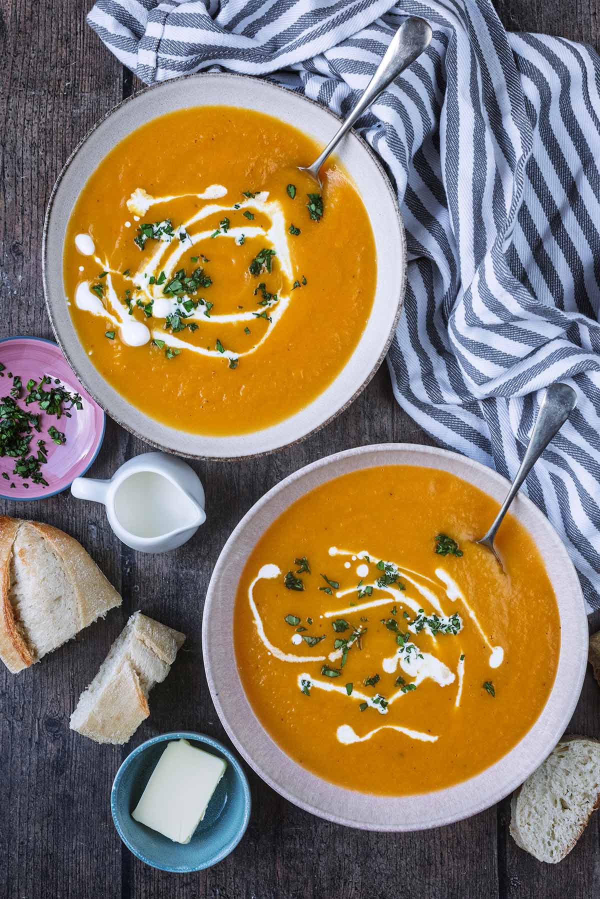 Two bowls of sweet potato and butternut squash next to a striped towel.