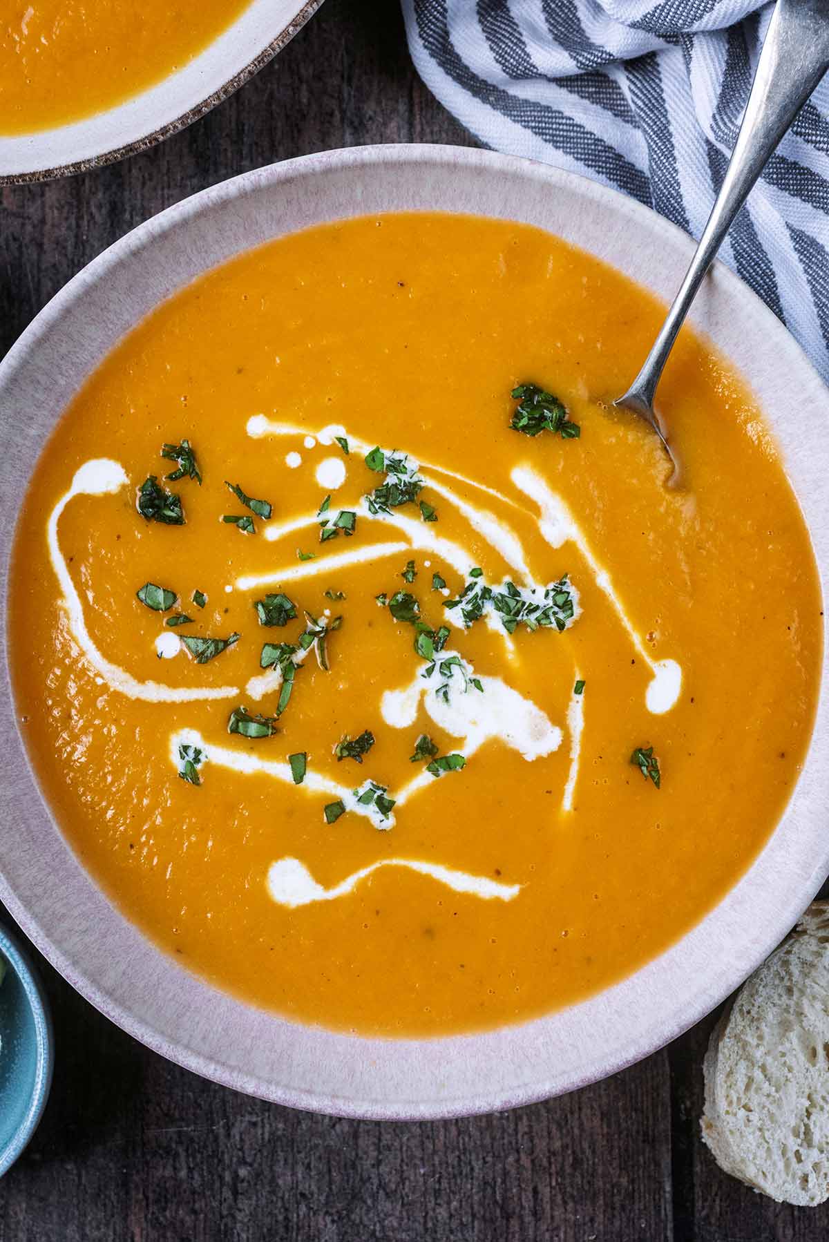 Chopped herbs and a drizzle of cream on top of sweet potato soup.