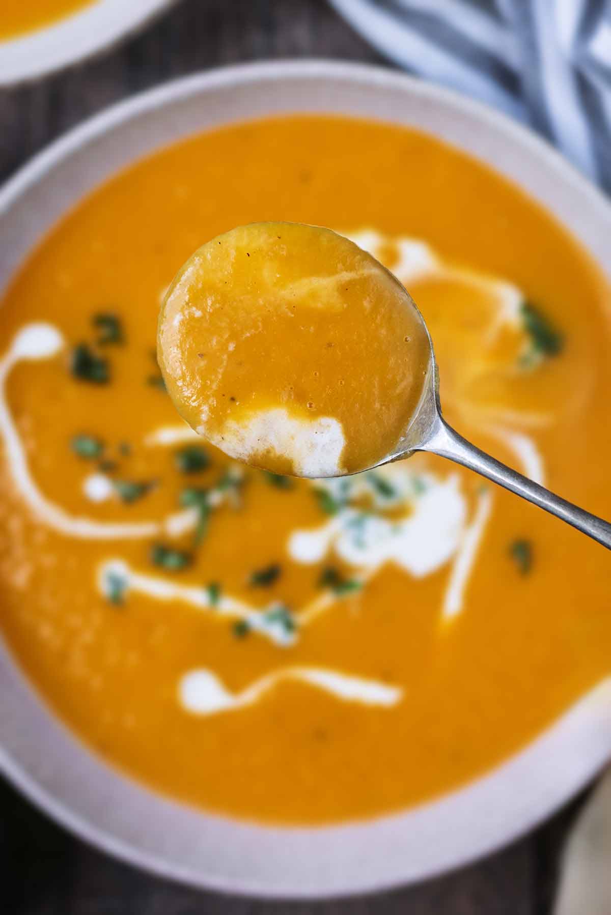 A spoon lifting some soup out of a bowl.