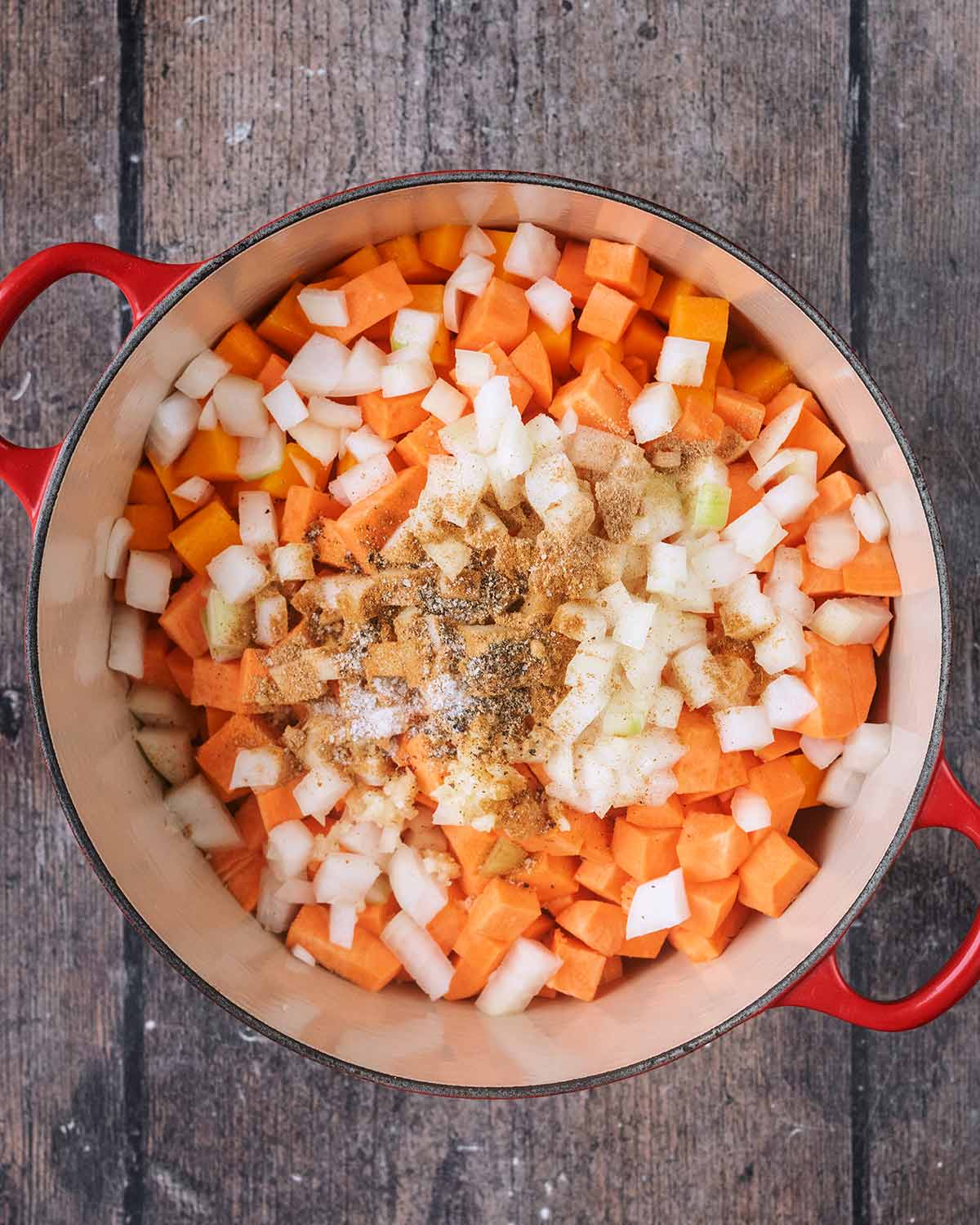 Chopped onion, sweet potato, butternut squash and seasoning in a large pot.