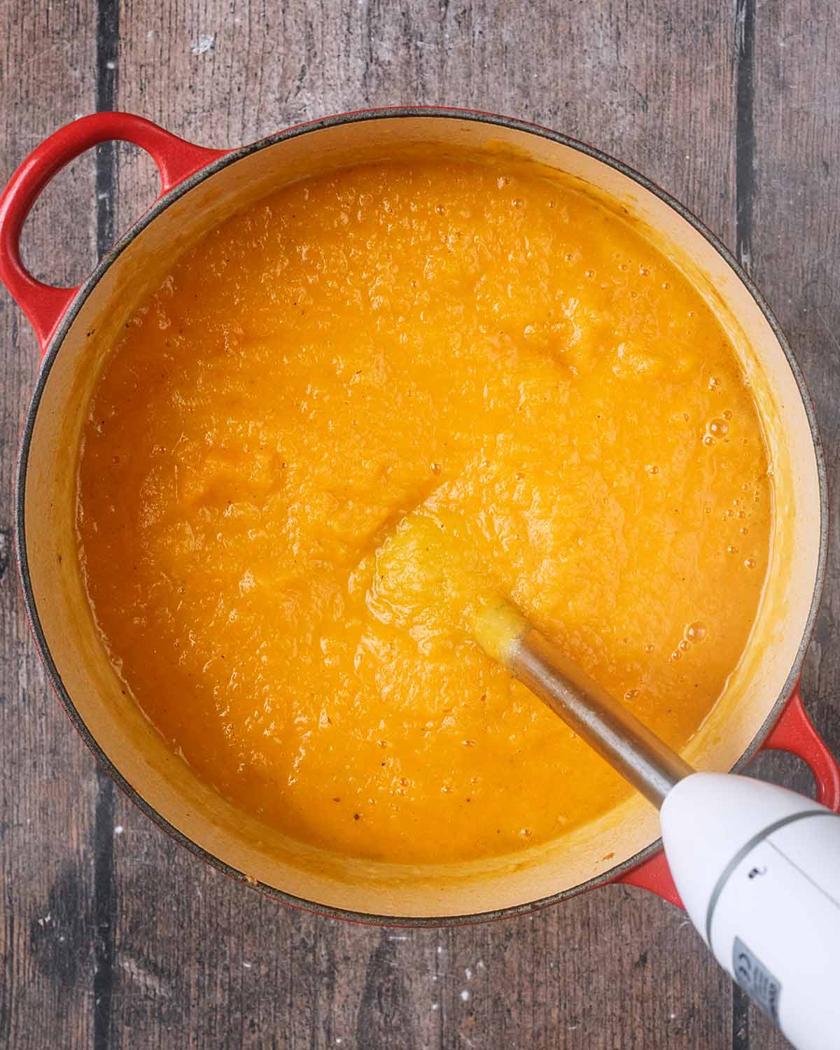 An immersion blender in the pot of soup.