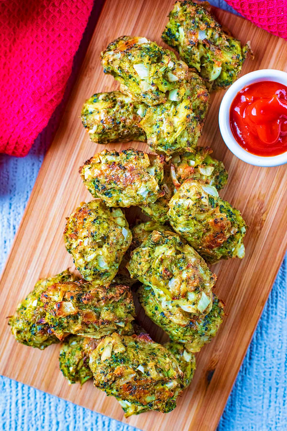 A wooden serving board piled high with Broccoli Bites.