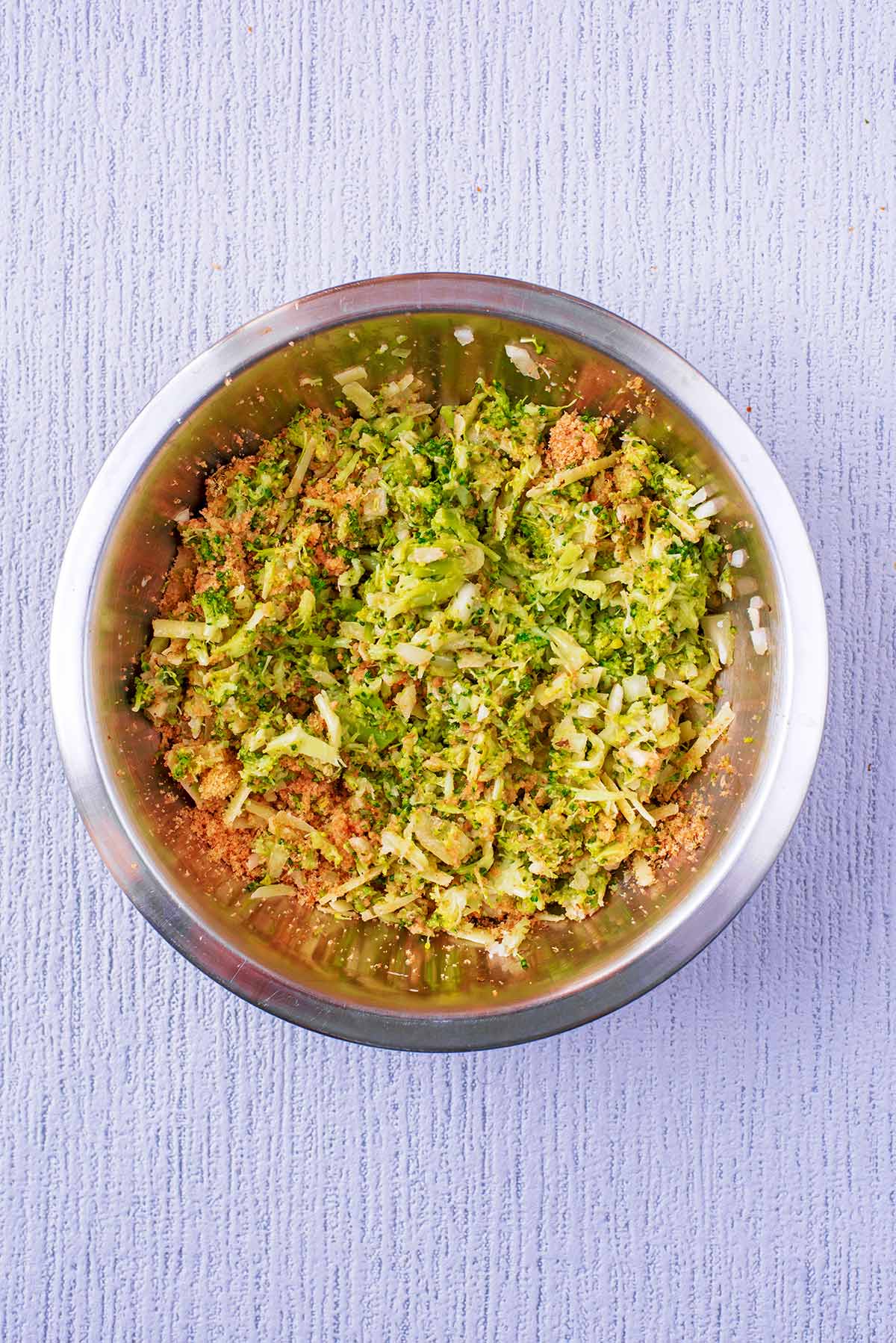 Broccoli, onion, breadcrumbs and cheese all mixed together in a bowl.