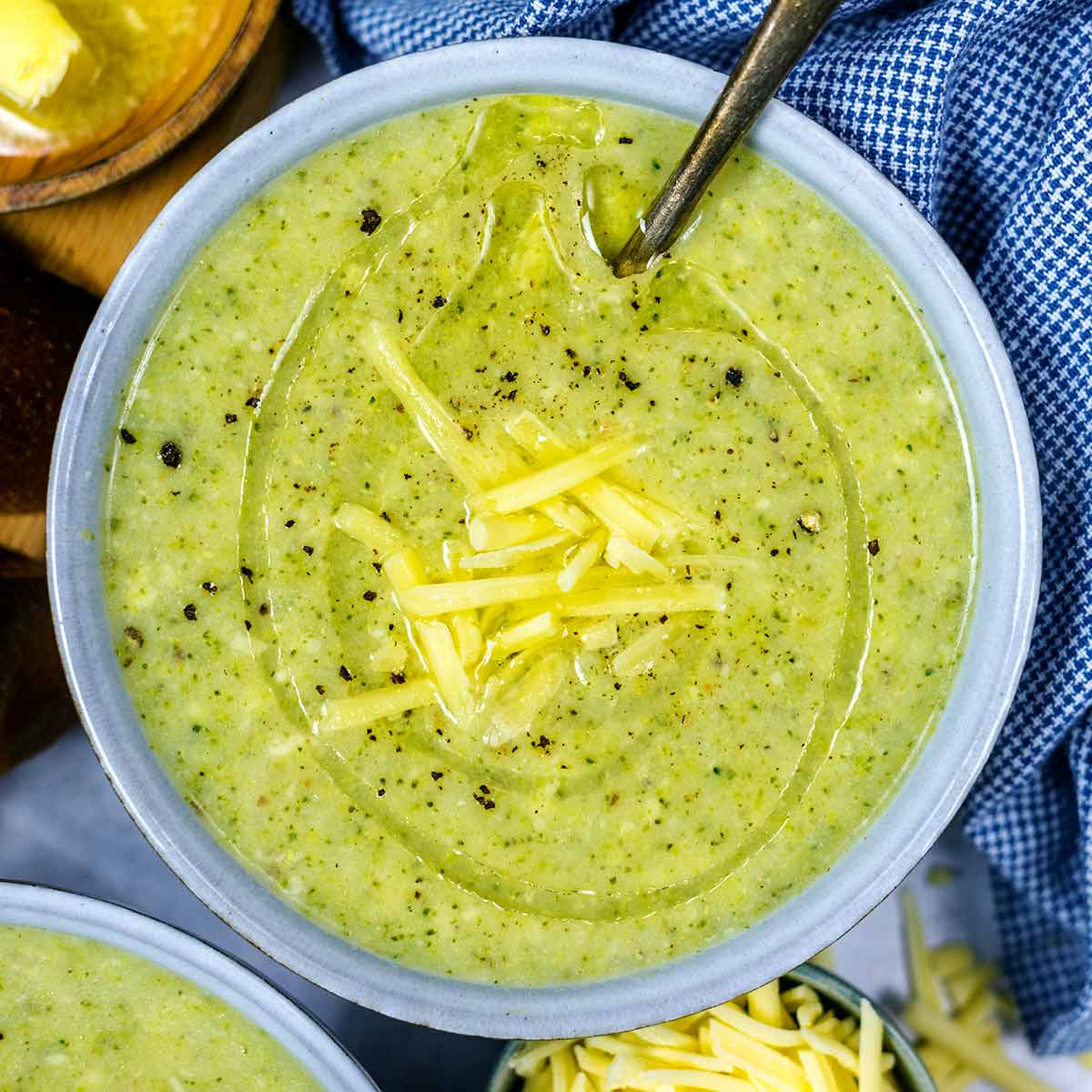 The soup in a bowl with more cheese on top and a spoon in the bowl.