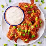Oven baked bbq chicken wings on a plate with some dip.
