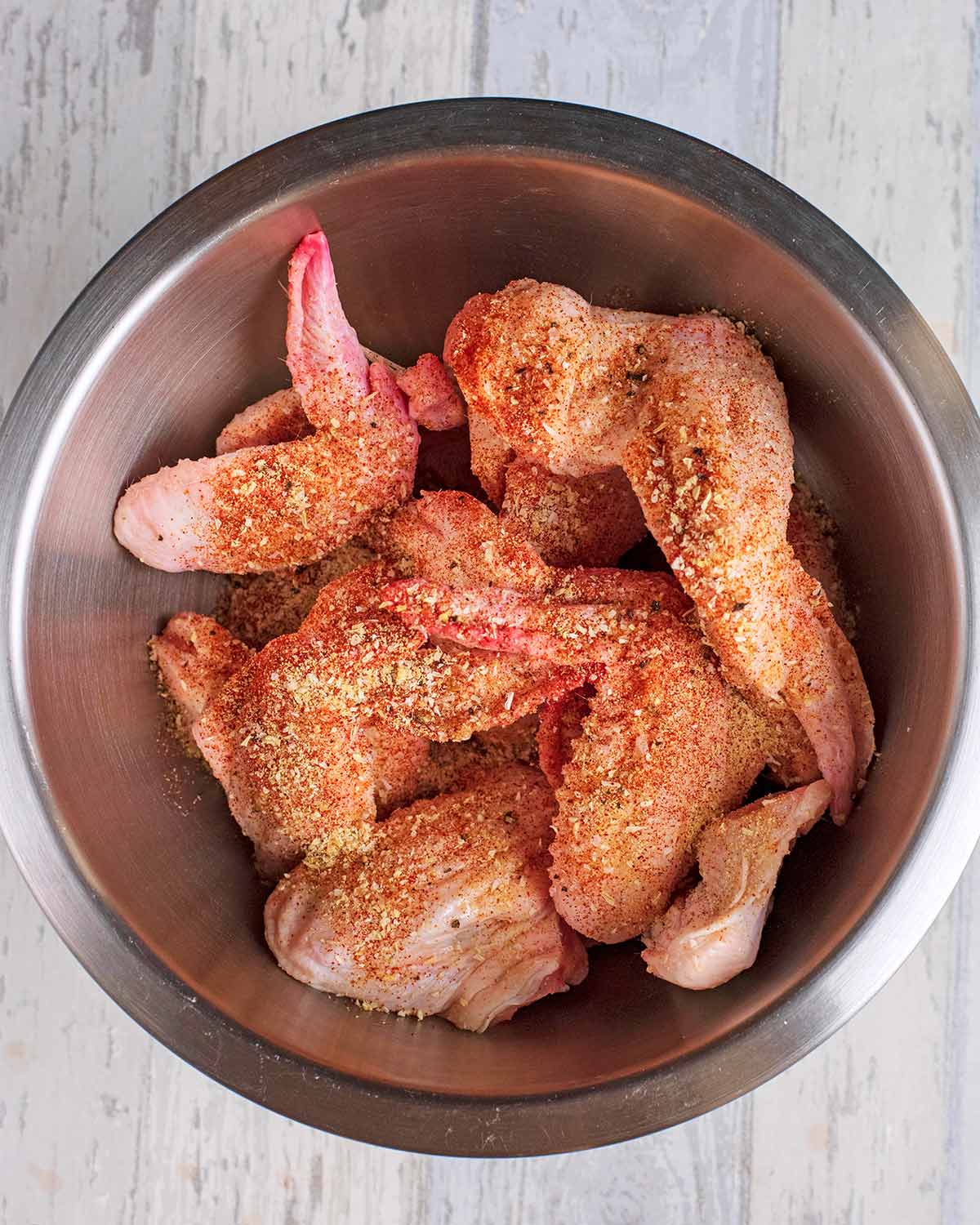 A bowl containing chicken wings coated in seasoning.