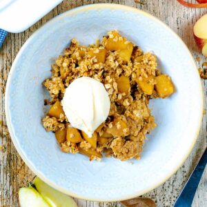 A bowl of Apple Crumble with oats with a ball of ice cream on top.