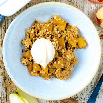 A bowl of Apple Crumble with oats with a ball of ice cream on top.