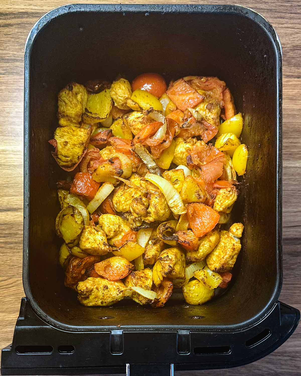 Cooked chicken and vegetables in the air fryer basket.