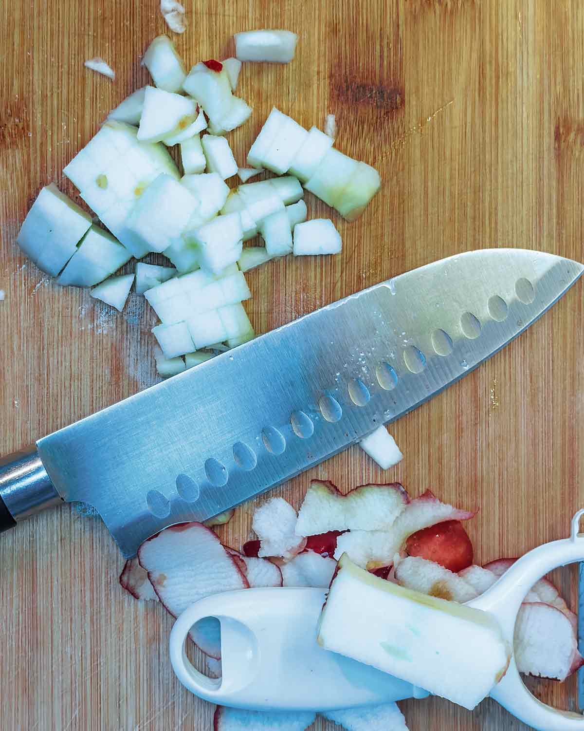 Apples chopped into small cubes on a chopping board.