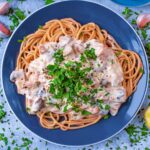A blue plate with creamy mushroom pasta on it.