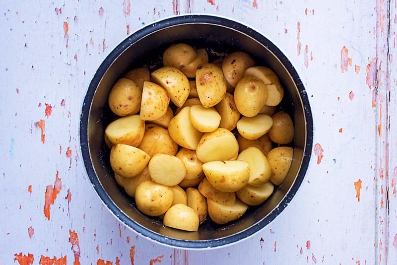 A saucepan full of halved new potatoes.
