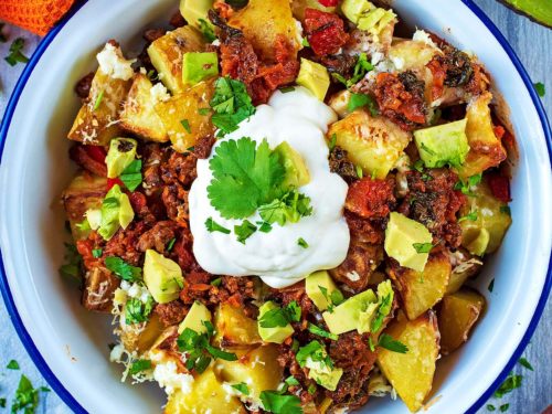 Mexican Beef and Potato Bake in a bowl sat on a wooden surface.