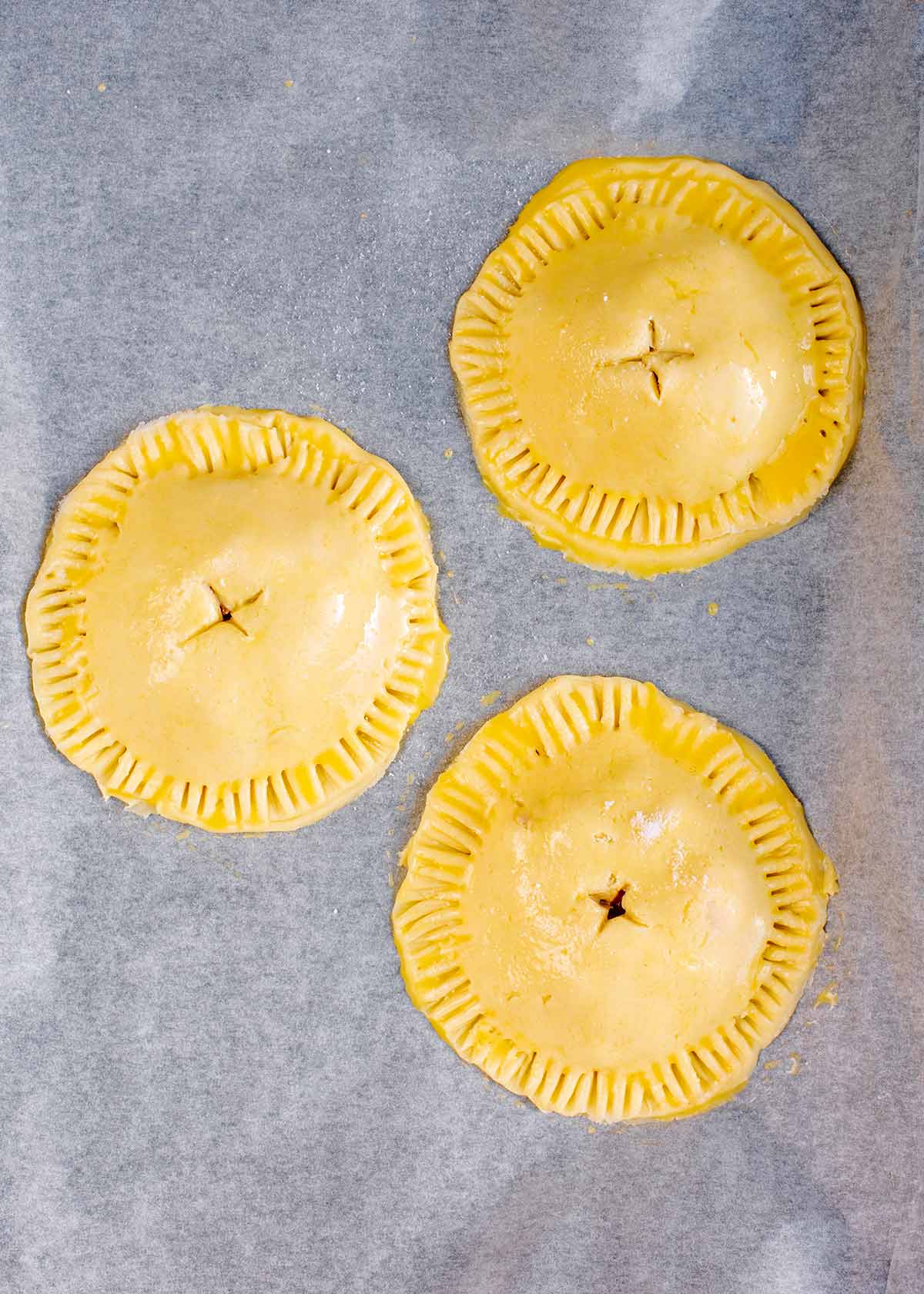 Uncooked hand pies on a baking tray.
