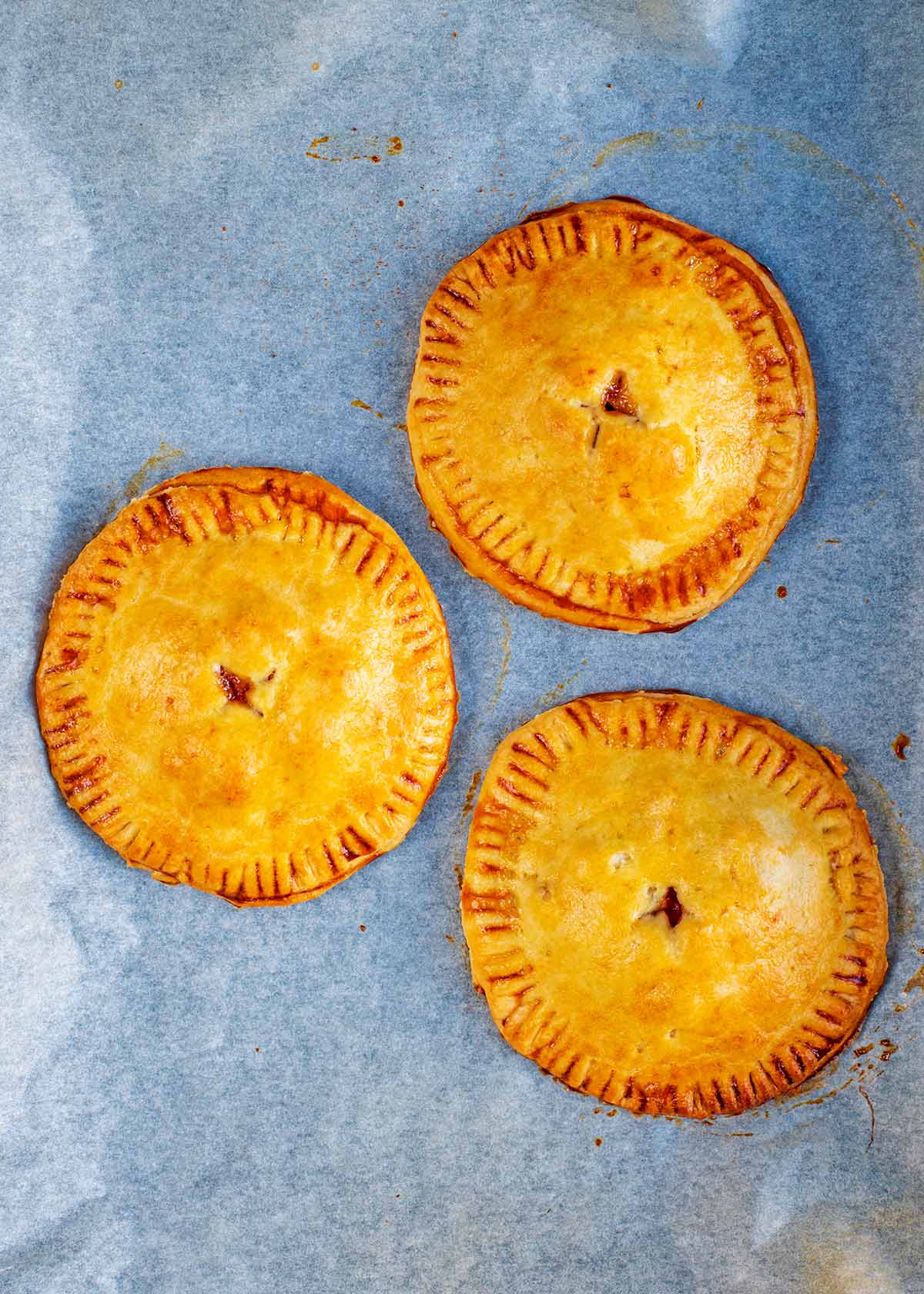 Three cooked hand pies on a baking sheet.