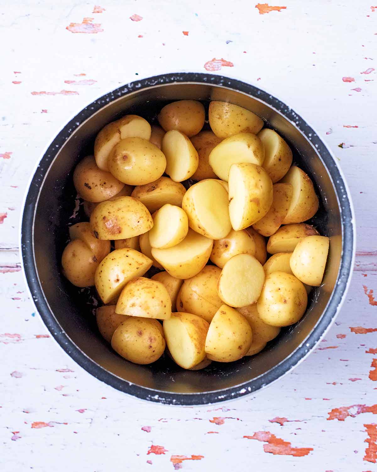 A saucepan full of halved new potatoes.