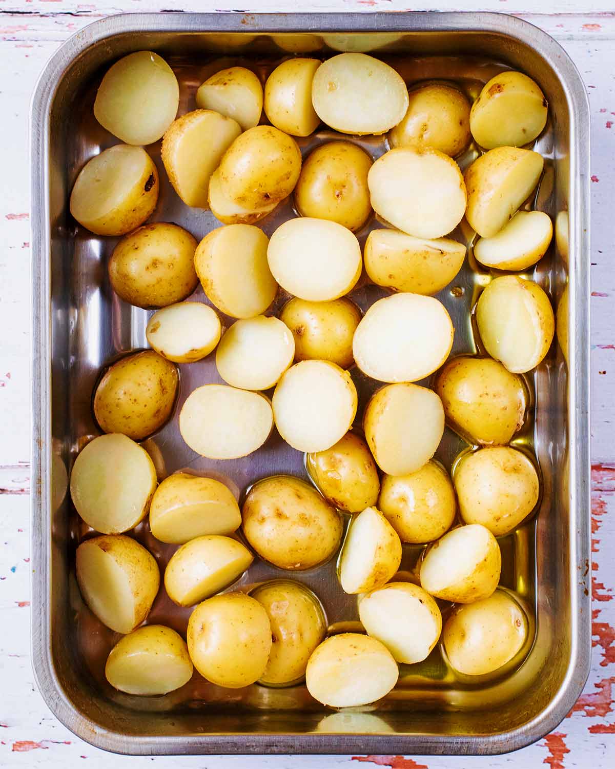 A roasting tin full of halved new potatoes.