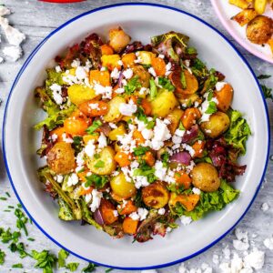 Roasted Vegetable Winter Salad in a white dish surrounded by crumbled feta.