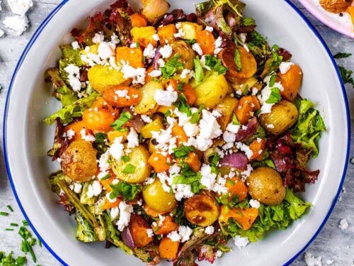 Roasted Vegetable Winter Salad in a white dish surrounded by crumbled feta.