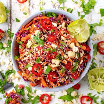 Asian Slaw in a blue bowl surrounded by sliced chillies and herbs.