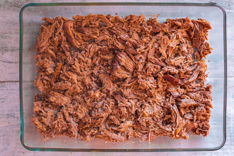Shredded lamb meat in a large glass dish.