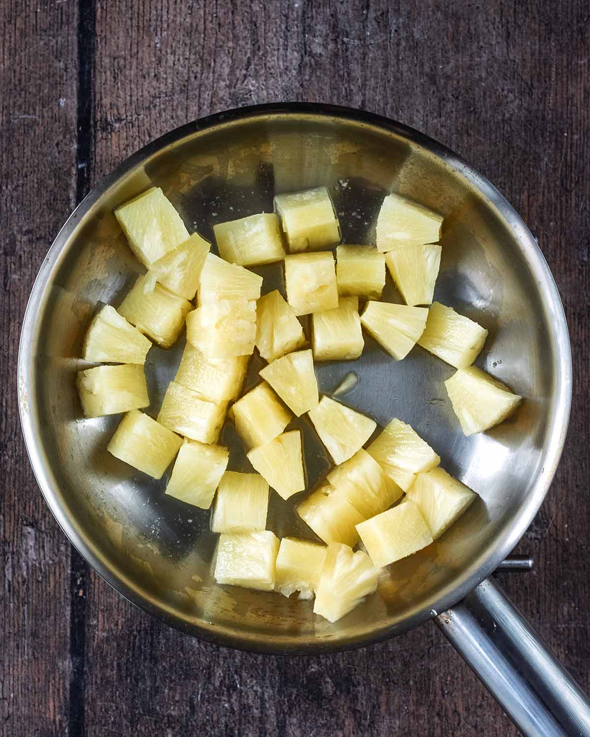 Pineapple chunks cooking in a frying pan.