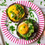 Eggs Baked in Portobello Mushrooms sat on a red and white plate.