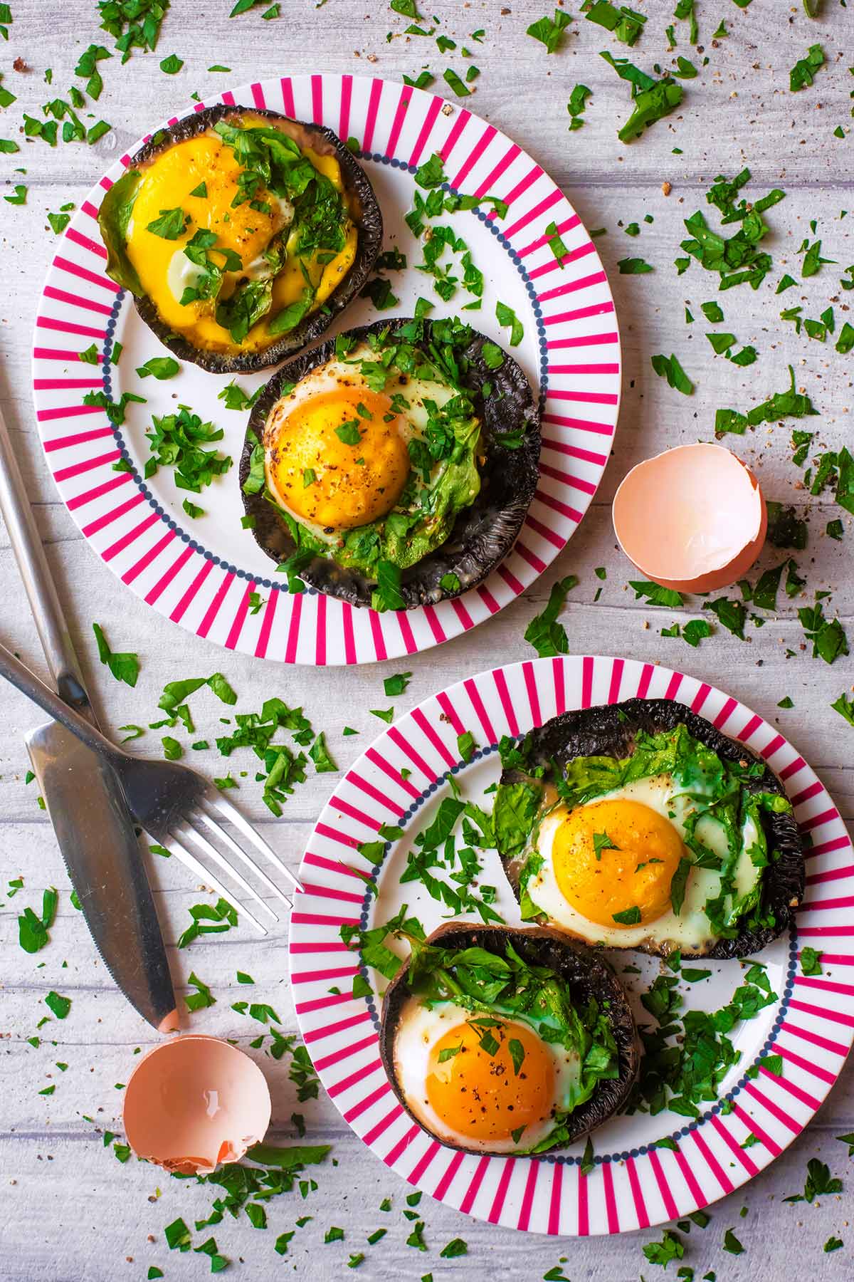 Two plates each with two Portobello Mushrooms with eggs in them.