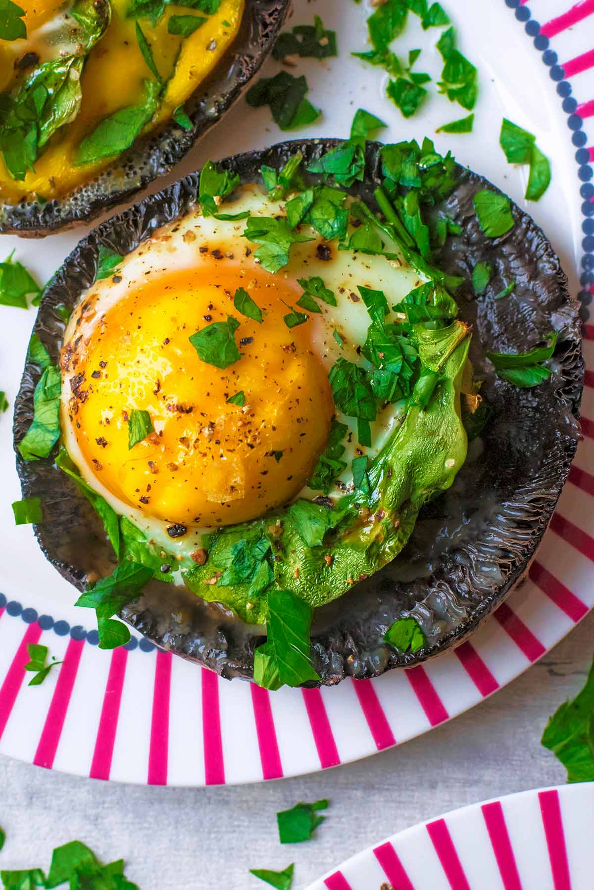 A baked egg in a large upturned mushroom topped with chopped herbs.