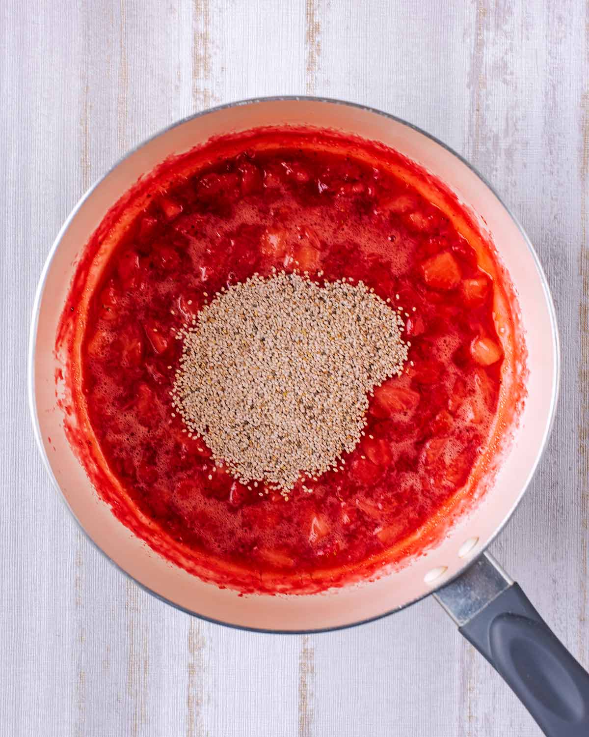 Mashed strawberries and chia seeds in a saucepan.