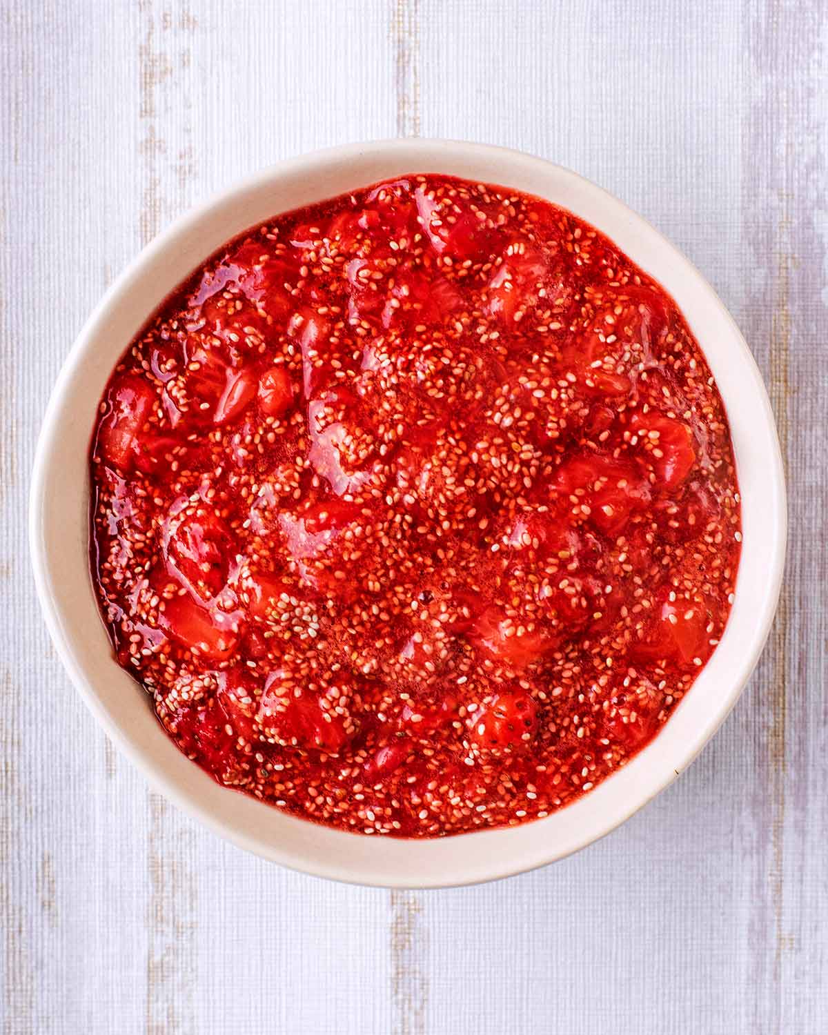 Strawberry chia jam in a round white bowl.